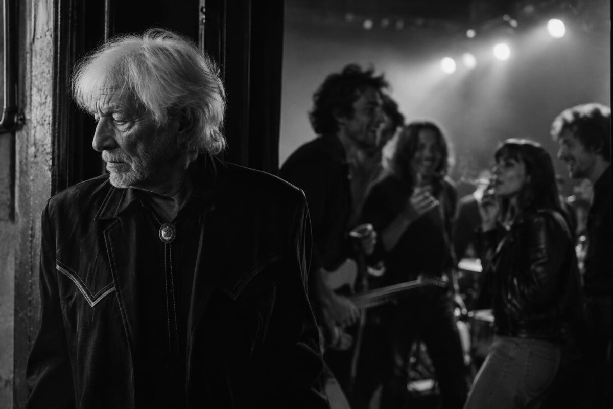 Hugues Aufray à l'écart de la fête dans un music-hall des années 1960 (image générée par IA)
